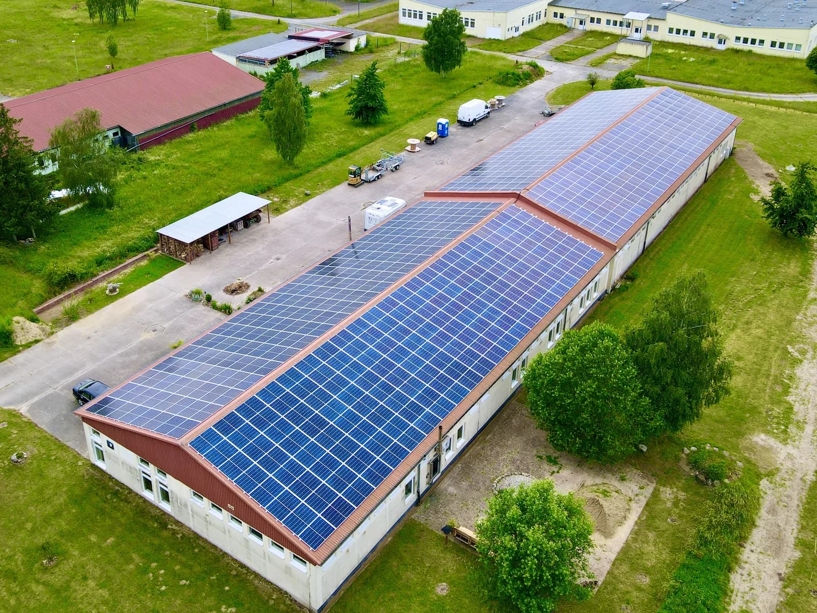 Luftaufnahme: langgestreckte Halle mit vollständig belegtem Photovoltaik-Dach
