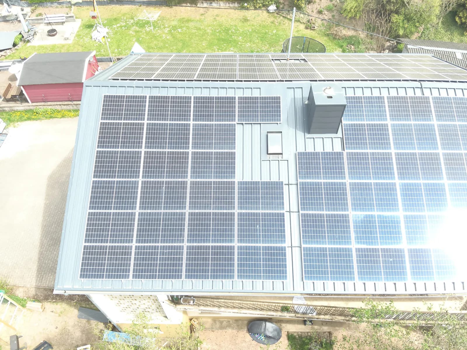 Drohnenaufnahme von oben: PV-Module in Reihen auf einem Metalldach