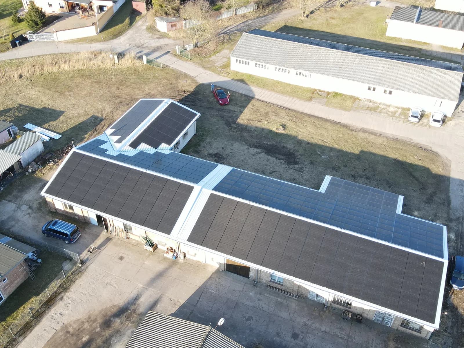 Luftaufnahme: landwirtschaftliche Halle mit großer Photovoltaikanlage auf dem Dach
