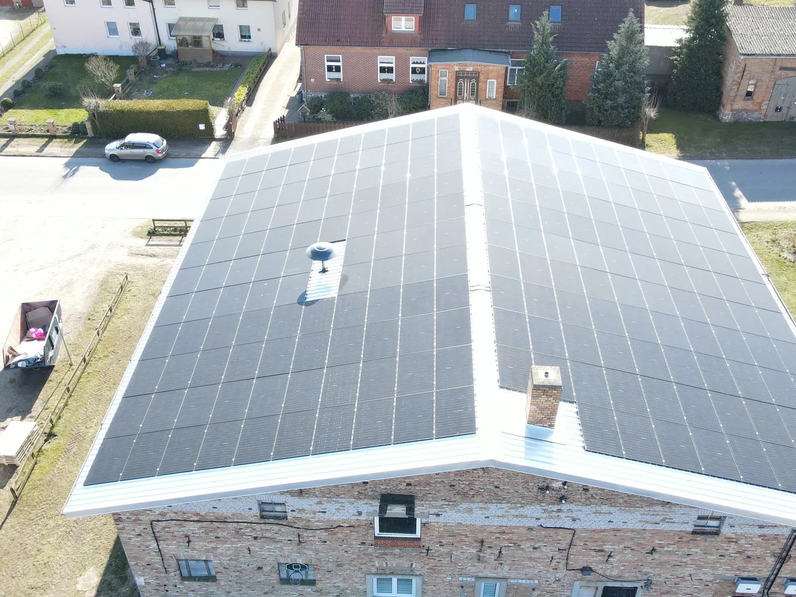 Luftaufnahme: Gebäude mit Photovoltaikanlage auf dem Dach in ländlicher Umgebung