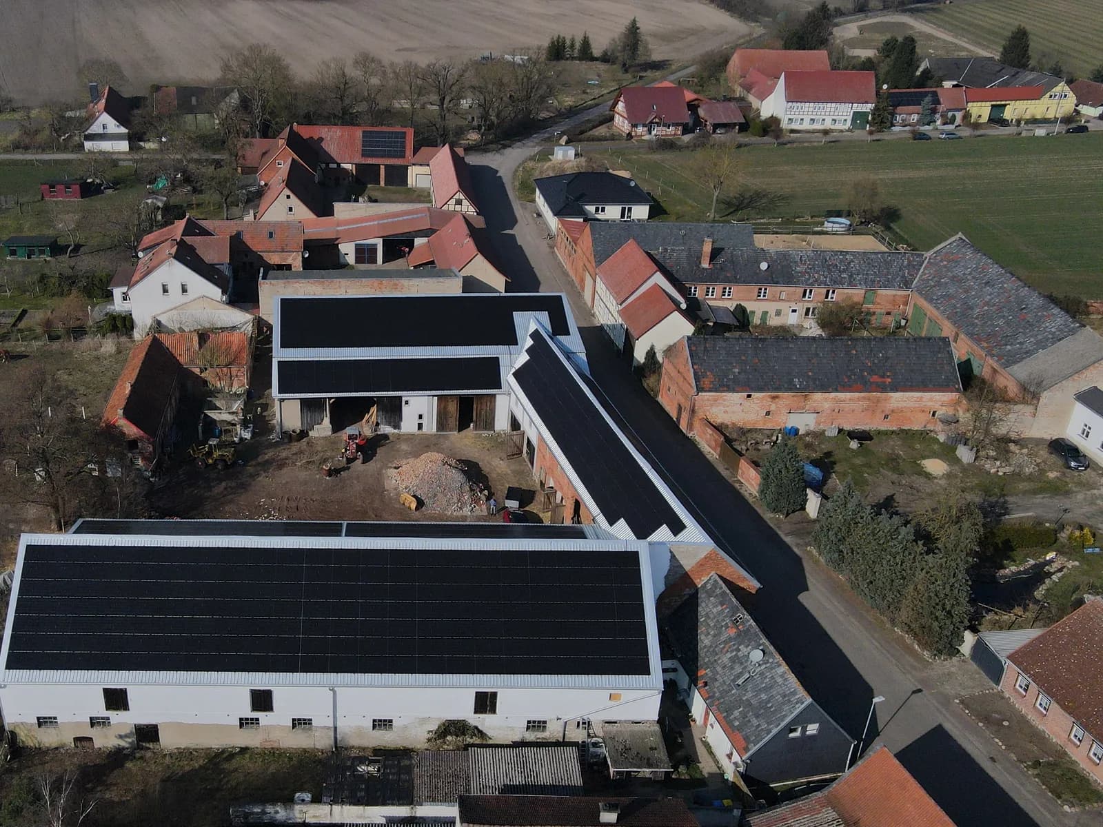 Luftaufnahme: mehrere Hallendächer eines Hofs mit Photovoltaikanlage